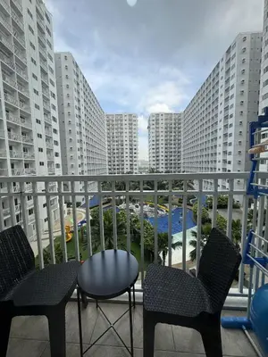 a balcony with chairs and tables and buildings at Shore Oasis Manila Near Mall of Asia in Manila