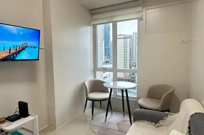 a living room with a table and a tv on a wall at Welcome to Jade Place at Pioneer Woodlands in Manila