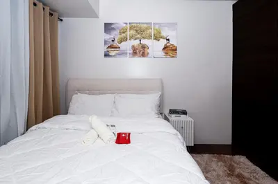 a white bed with a red cup on top of it at On Promo Condo 1BR Makati in Manila