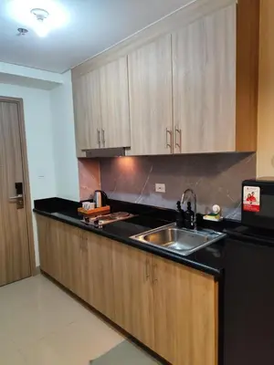 a kitchen with wooden cabinets and a sink at Comfort Cove PH in Manila
