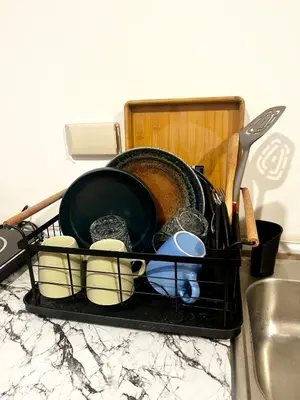 a dish drying rack with dishes and utensils on a kitchen counter at Bali Inspired near BGC and NAIA in Manila