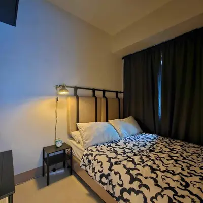 a bedroom with a bed with a black and white comforter at Cozy Minimalist Unit at SMDC Shore 3 in Manila