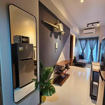 a room with a kitchen with a refrigerator and a living room at Cozy Minimalist Unit at SMDC Shore 3 in Manila