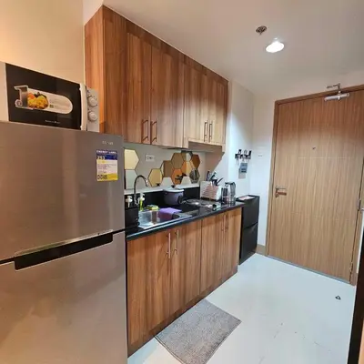 a kitchen with wooden cabinets and a stainless steel refrigerator at Cozy Minimalist Unit at SMDC Shore 3 in Manila
