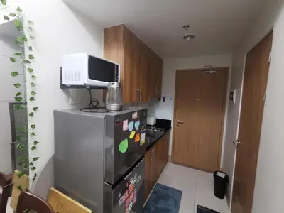 a kitchen with a refrigerator with a microwave on top of it at aldo shore 3 residence mall of asia in Manila