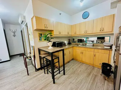 a kitchen with wooden cabinets and a table in it at Cozy 2-BR Perfect for Families and Friends in Manila