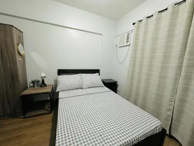 a bedroom with a bed and a table and a window at Cozy 2-BR Perfect for Families and Friends in Manila
