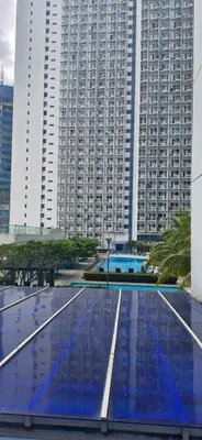 a large building with tall buildings in the background at SM JAZZ RESIDENCES-Urban Escape in Manila