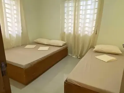 two beds in a room with two windows at Home of Joy Villa Peace House in Dasmariñas