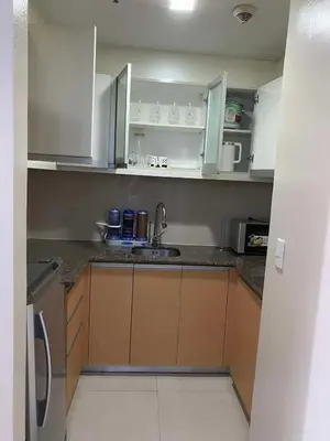 a small kitchen with white cabinets and a sink at JOVYNOEL Condominium Unit Rental in Manila
