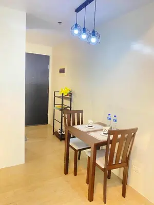 a dining room with a wooden table and two chairs at JOVYNOEL Condominium Unit Rental in Manila