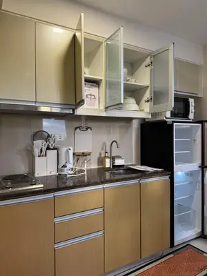 a kitchen with brown cabinets and a black refrigerator at 1BR Condo Near Venice Canal & BGC with Great View - 20k in Manila