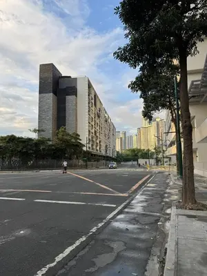 an empty street with a building and a tree at New 1BR Condo Near Venice Canal & BGC with Balcony - 7e in Manila