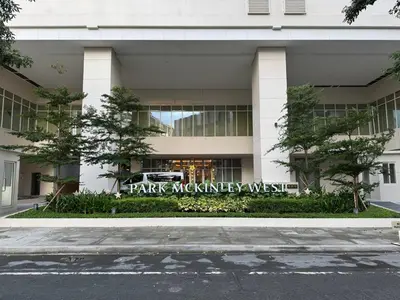 a white building with a park machineryweb sign on it at New 1BR Condo Near Venice Canal & BGC with Balcony - 7e in Manila