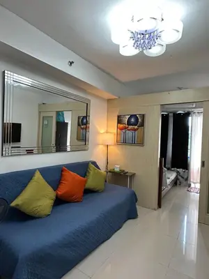 a living room with a blue couch with colorful pillows at Staycation Near Moa by Jen in Manila