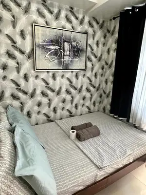 a bed with a towel and a picture on a wall at Staycation Near Moa by Jen in Manila