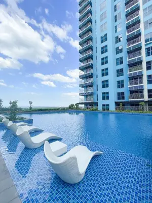 a hotel swimming pool with white chairs in front of a building at Luxury 2BR Corner near Solaire & Okada II Sunset in Manila
