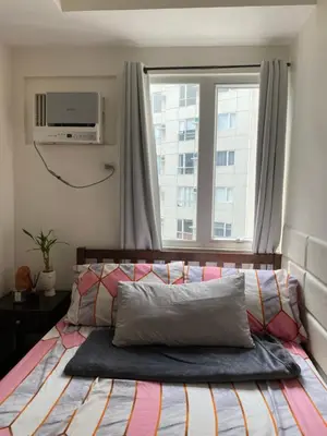 a bedroom with a bed with a television on the wall at Staycation in Mandaluyong in Manila