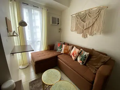 a living room with a brown couch and a table at Staycation in Mandaluyong in Manila