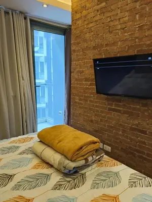 a bed with a pillow and a flat screen tv on a brick wall at LDN Two Palm Tree Villas T3 in Manila