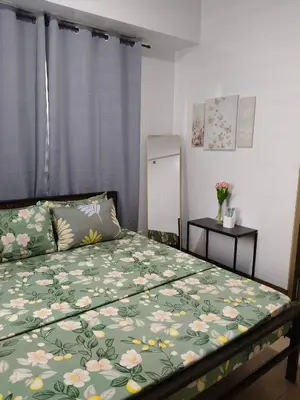 a bedroom with a bed with a green floral bedspread at LDN TWO Palm Tree Newport City in Manila