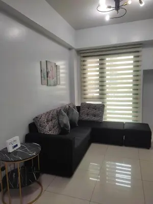 a black couch in a living room with a window at LDN TWO Palm Tree Newport City in Manila