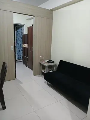 a living room with a black couch and a table at Breeze Residences in Manila