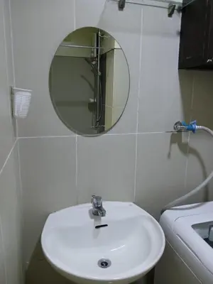 a bathroom with a white sink and a mirror at Breeze Residences in Manila