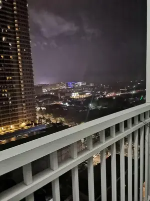 a view of a city at night from a balcony at Breeze Residences in Manila