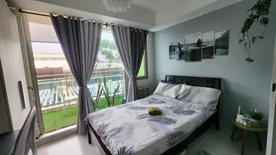 a bedroom with a bed and a large window at Jellybean's Snuggly Cabin in Manila
