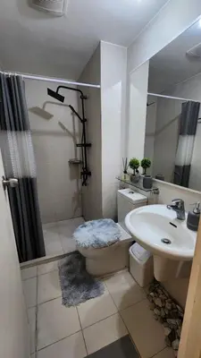 a bathroom with a toilet and a sink and a shower at Jellybean's Snuggly Cabin in Manila
