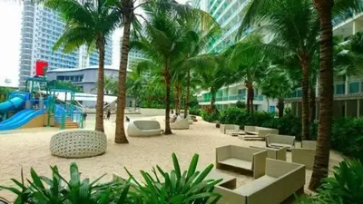 a resort with a playground with palm trees and a slide at Jellybean's Snuggly Cabin in Manila