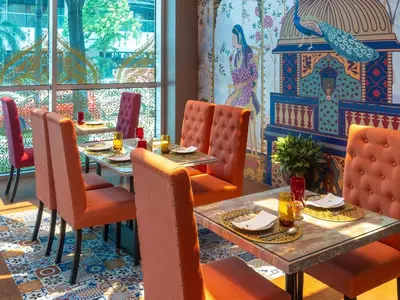 a dining room with two tables and orange chairs at Novotel Manila Araneta City Hotel in Manila