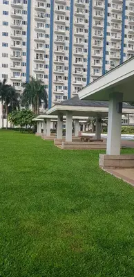 a building with a green field in front of tall buildings at 1Br Fully Furnished Condo Unit at Light Residences in Manila