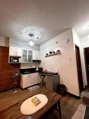 a living room with a table and a kitchen at Mckinley Taguig Staycation in Manila