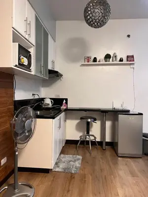a kitchen with a sink and a desk with a fan at Mckinley Taguig Staycation in Manila