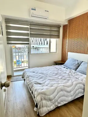 a bedroom with a large bed and a window at South Residences Tower in Manila