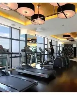 a gym with several treadmills and a woman in the background at Maleel Rentals in Manila