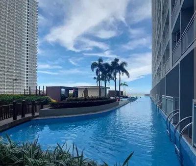 a swimming pool at a resort with palm trees at SMDC Breeze Residences in Manila
