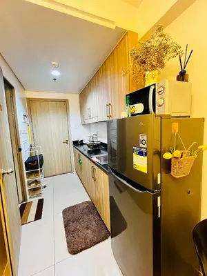 a kitchen with a black refrigerator and wooden cabinets at Affordable staycation at SHORE RESIDENCES Near MOA and NAIA in Manila
