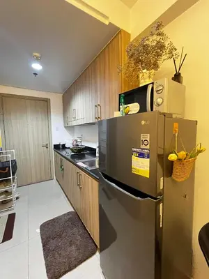 a kitchen with a stainless steel refrigerator and wooden cabinets at Affordable staycation at SHORE RESIDENCES Near MOA and NAIA in Manila
