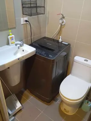a small bathroom with a toilet and a sink at Condo next door in Manila