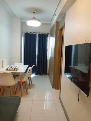 a living room with a table and a television on a wall at Condo next door in Manila