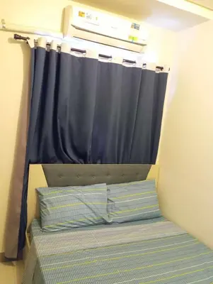 a bed in a room with a blue curtain at Condo next door in Manila