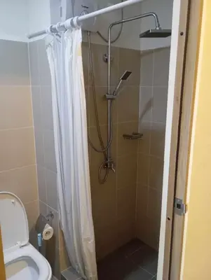 a bathroom with a shower with a toilet and a shower curtain at Condo next door in Manila