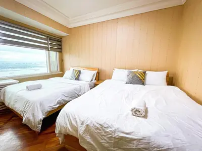 two beds in a room with a window at Stunning & Luxury 4BR in Manila Bay White Beach in Manila