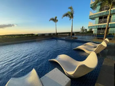 a swimming pool with white chairs and a building at Luxurious 2BR with Manila Bay Sunset II 6pax in Manila