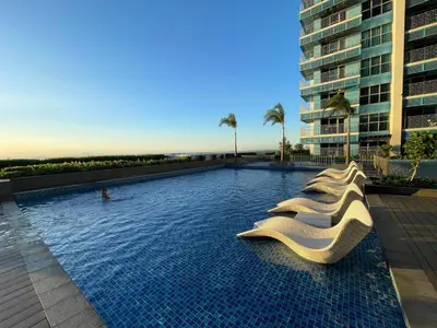 a swimming pool with white chairs in a building at Lovely & Modern 1BR in Manila across Okada in Manila