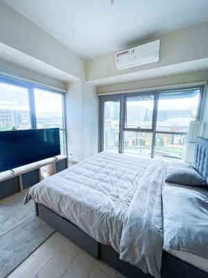a bedroom with a large bed and a flat screen tv at Luxury 2BR Corner near Solaire & Okada II Sunset in Manila