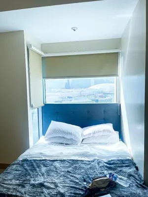 a bed in a room with a large window at Luxury 2BR Corner near Solaire & Okada II Sunset in Manila